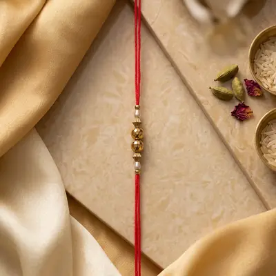 Red Thread Rakhi with Golden and Pearl Beads